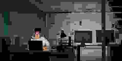 man sitting in the dark on a computer